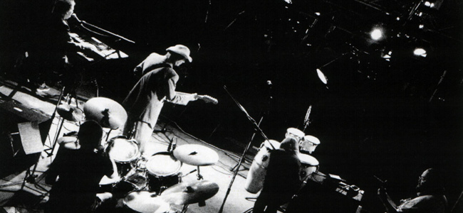 Pete mid-solo on a lit stage, seen from above the drum kit, black and white